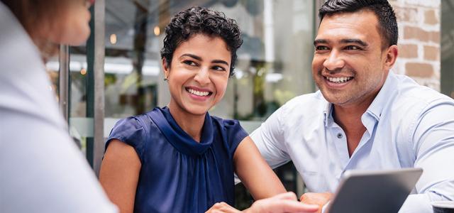 Three people sitting at a table smiling at each other